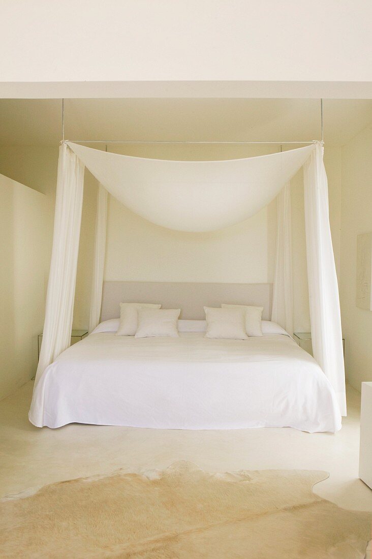 Purist sleeping area with drooping fabric canopy and side curtains in spartan room
