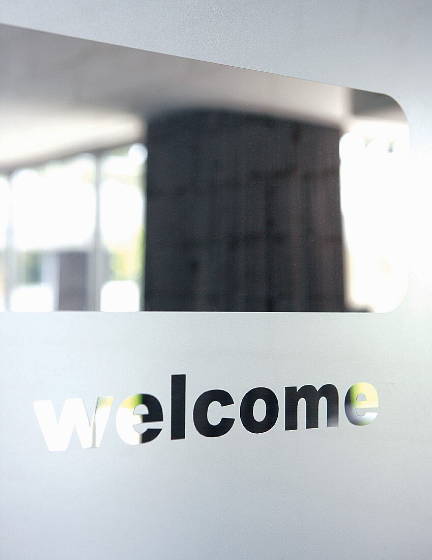 View through the clear glass of a frosted glass entrance door with 'welcome' engraved in it