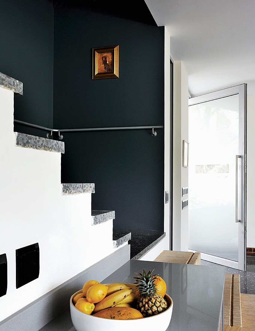 Mixture of plywood and stone steps in dark-painted niche with open glass door in background