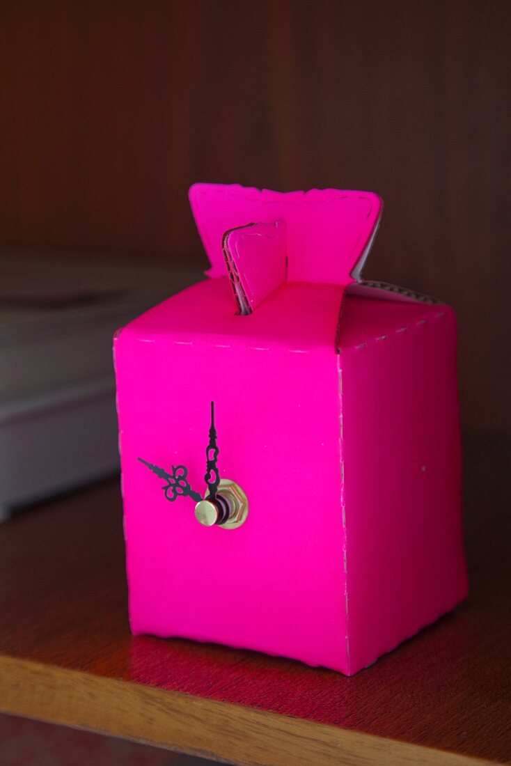 Neon pink clock made from gift box and ornate clock hands