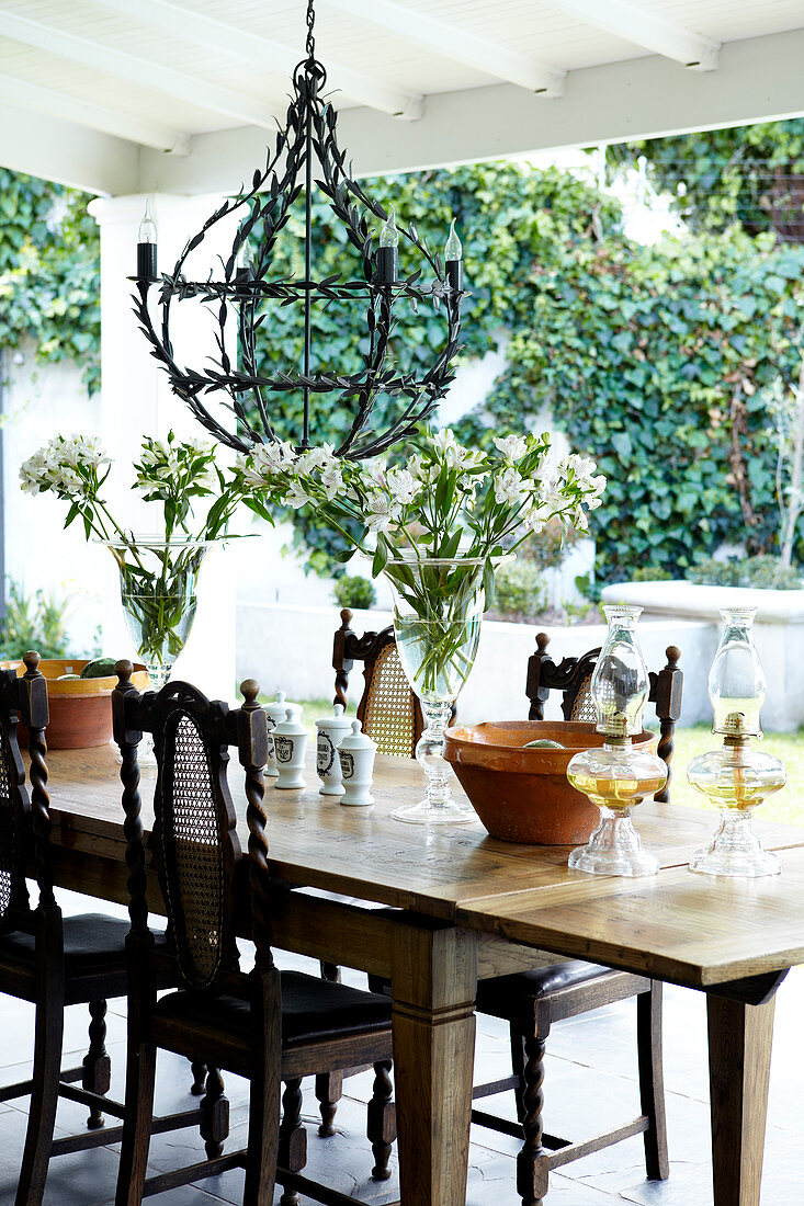 Stylish terrace, wrought iron lamp above a rustic, extension table with antique chairs