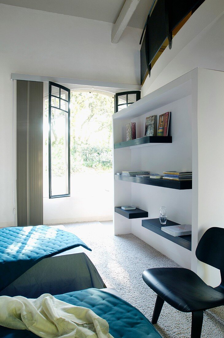 Guest room with white fitted shelving unit in front of open terrace door