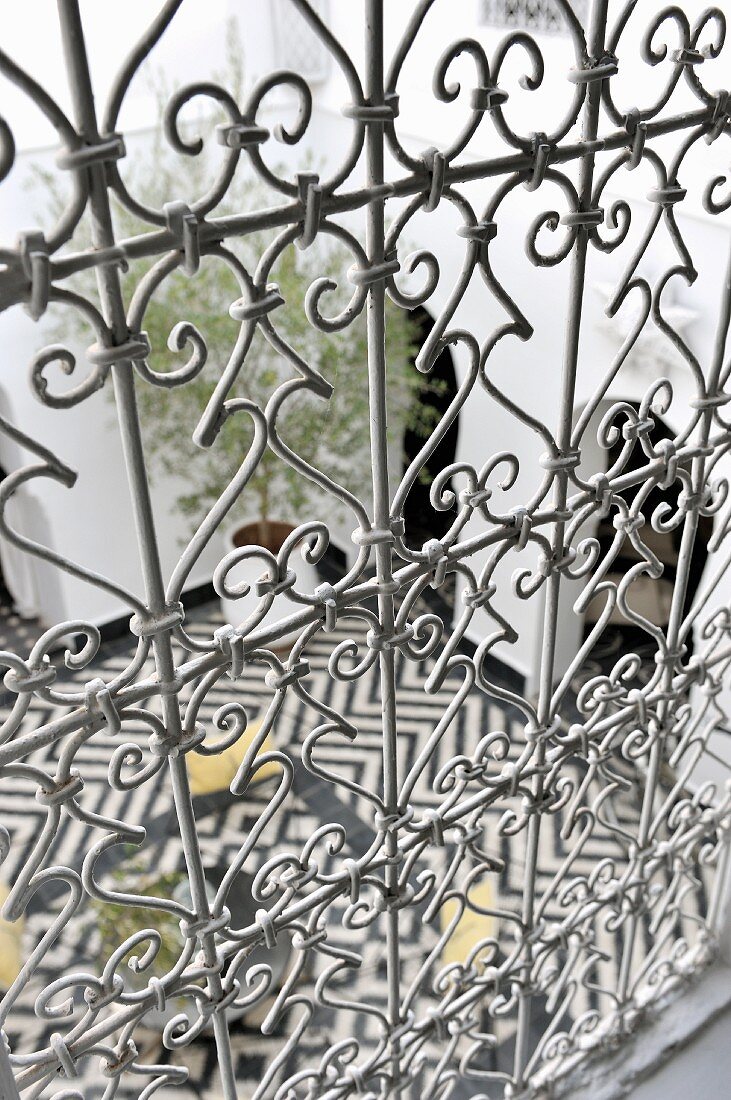 Blick durch ein kunstvoll gearbeitetes Eisendrahtgeländer in marokkanischen Innenhof
