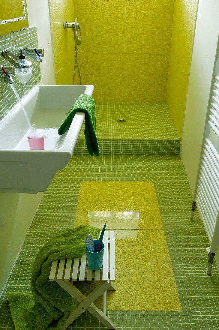 Schmales Bad mit grünen Mosaikfliesen und gelbgrün ausgekleideter, offener Dusche