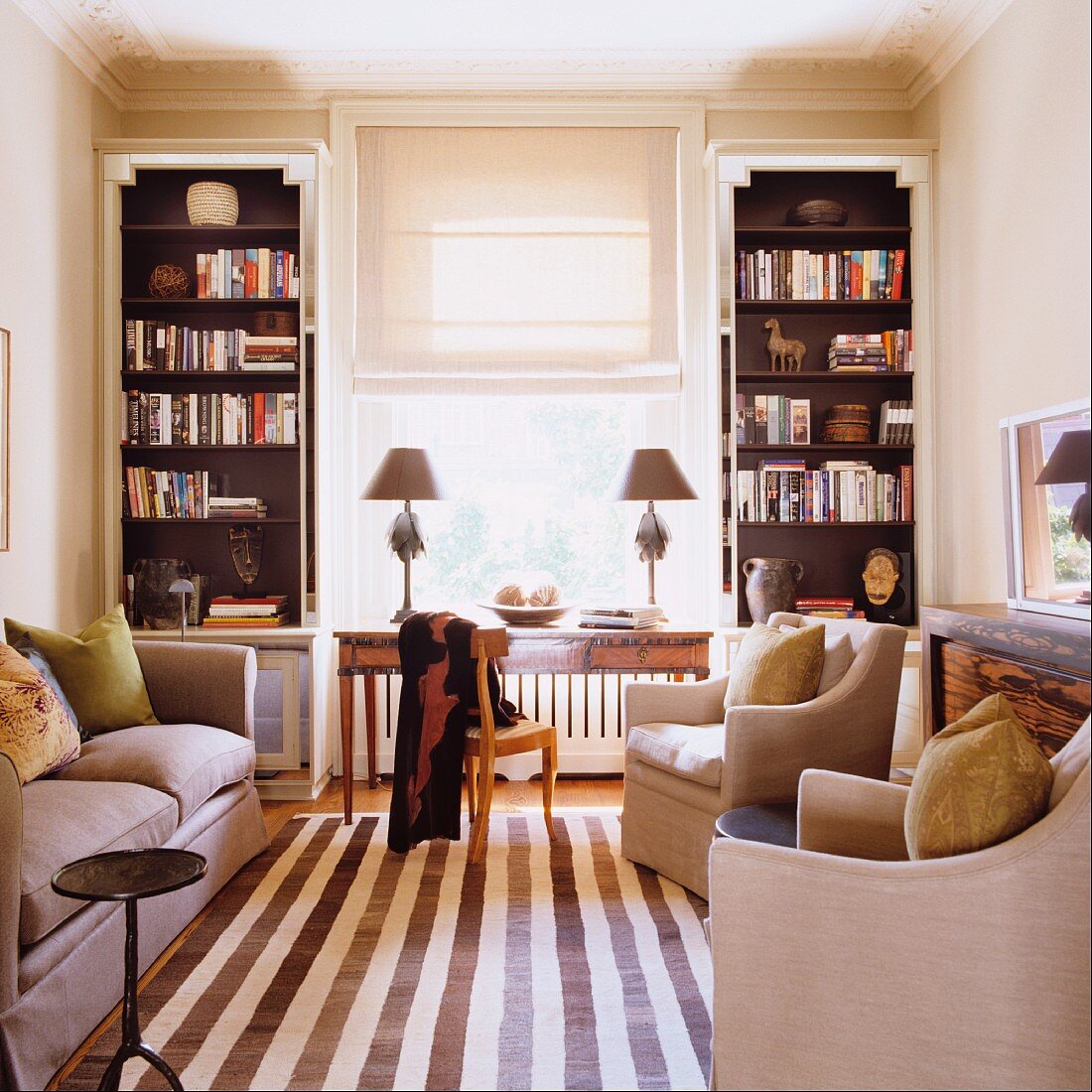Streifenteppichläufer zwischen Sofa und eleganten Sesseln im Wohnzimmer mit Regaleinbauten im Art Deco-Stil neben dem Fenster