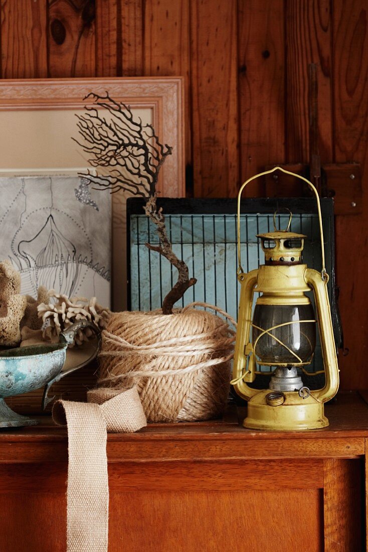 Oil lamps, twine and nautical decorative objects on a wooden chest of drawers