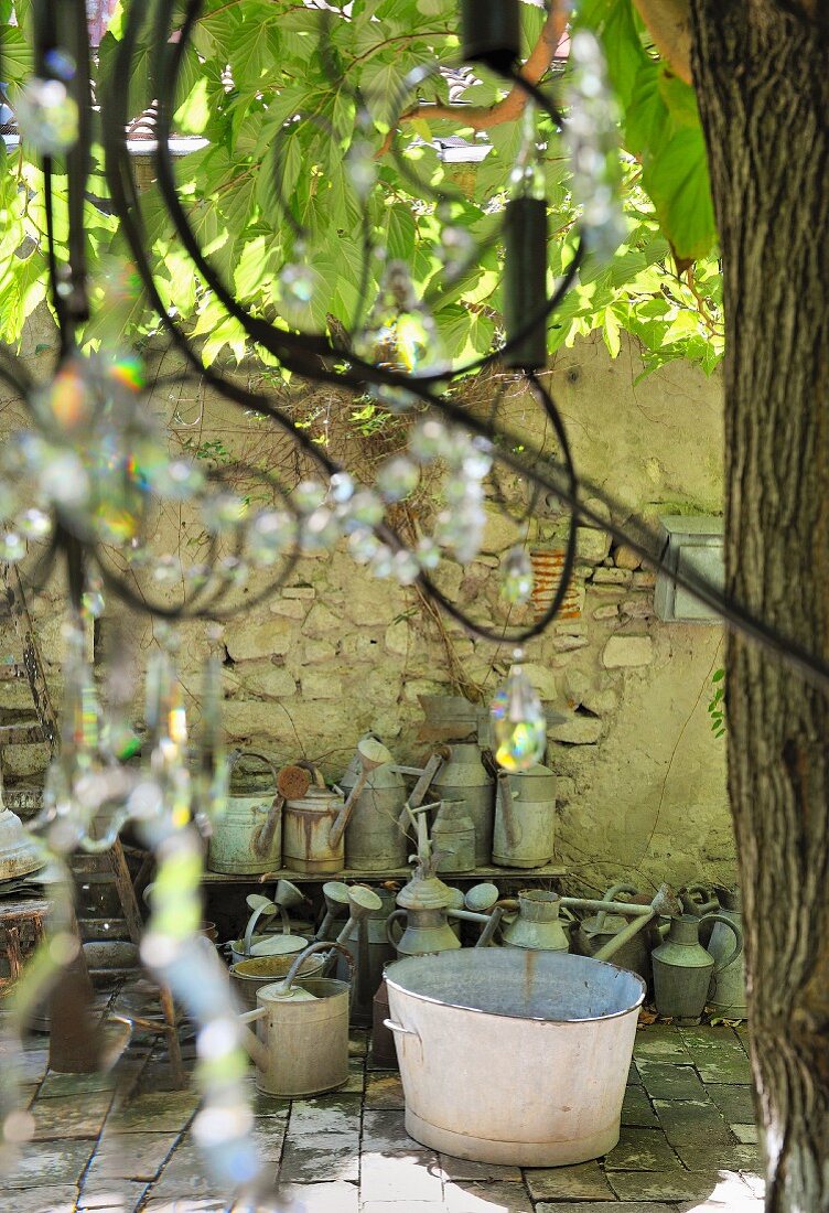 Zinc tubs and watering cans on floor against stone wall in vintage courtyard