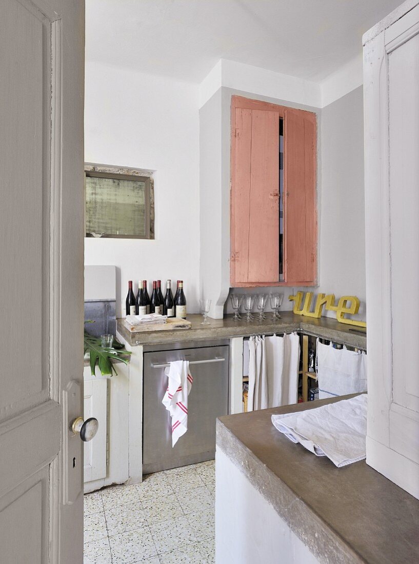 Blick durch offene Tür auf Küchenzeile mit eingebautem Schrank und hellroten Türen in schlichtem Ambiente