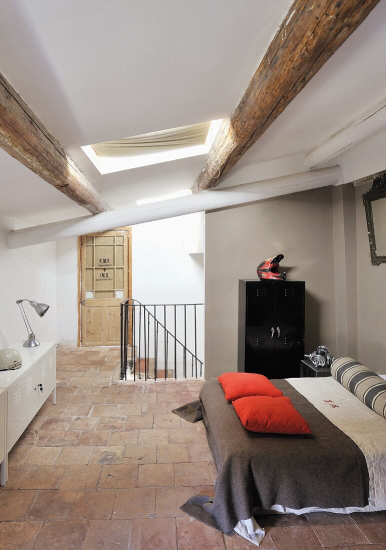 Offener Schlafbereich mit Doppelbett in renoviertem Dachgeschoss mit Holzbalkendecke in rustikalem Ambiente
