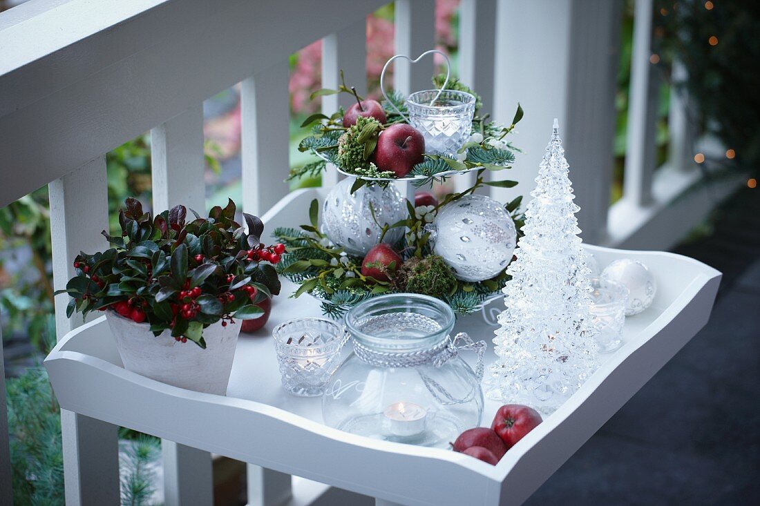 Christmas decorations on terrace: arrangement on cake stand, tealight holders, potted Gaultheria