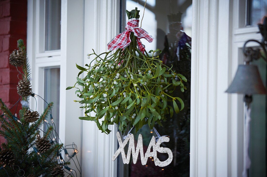 Branches of mistletoe hanging in front of front door as Christmas decoration
