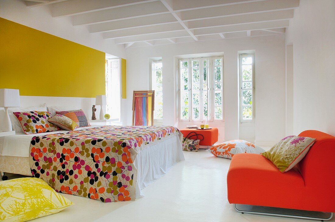 Gelbe und orangefarbene Töne zu weißem Boden und Holzdecke in geräumigem hellen Retro-Schlafzimmer
