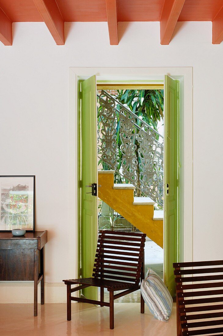 Slatted wooden chairs in front of green-painted exterior door