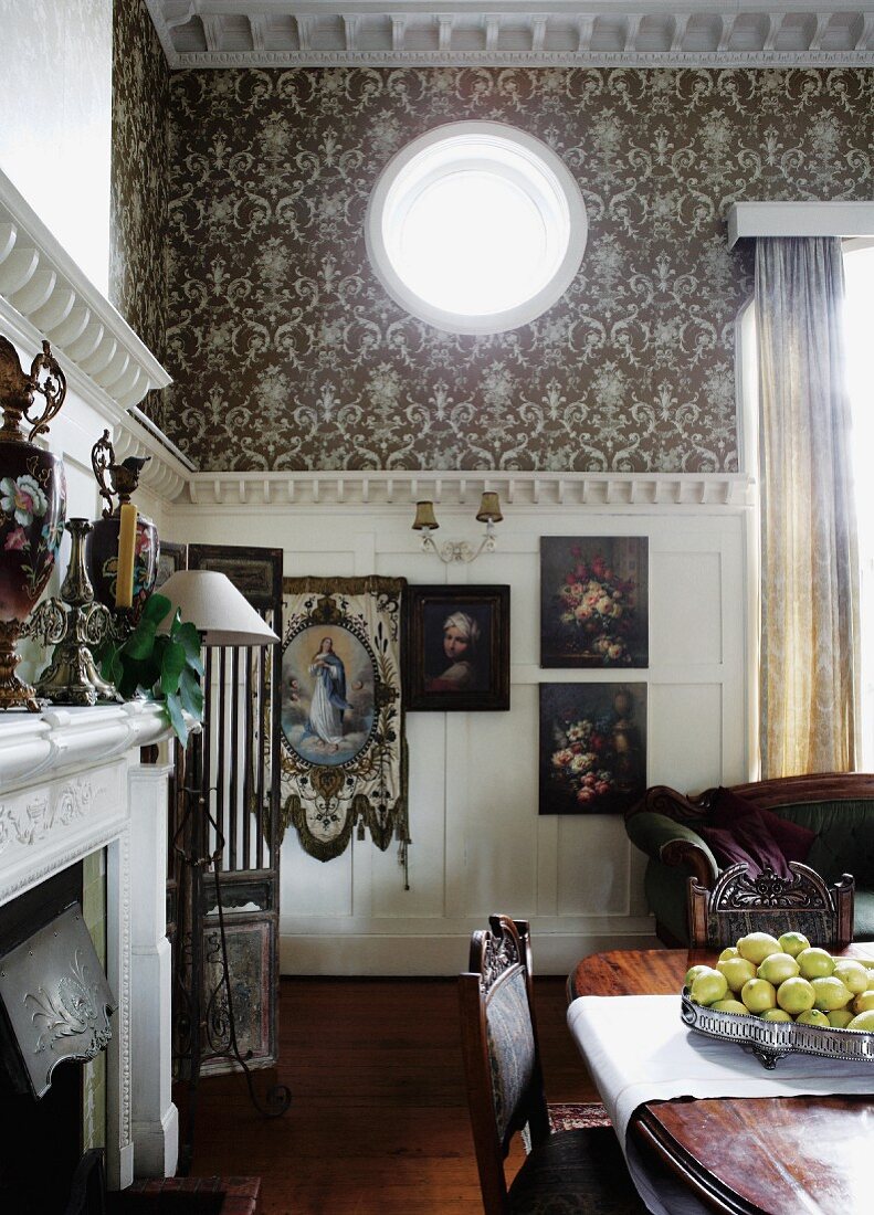 Pompöses Esszimmer mit halbhoher, weisser Holzverkleidung und kreisförmiges Oberlicht in Wand mit Ornamenttapete, davor teilweise sichtbarer Esstisch