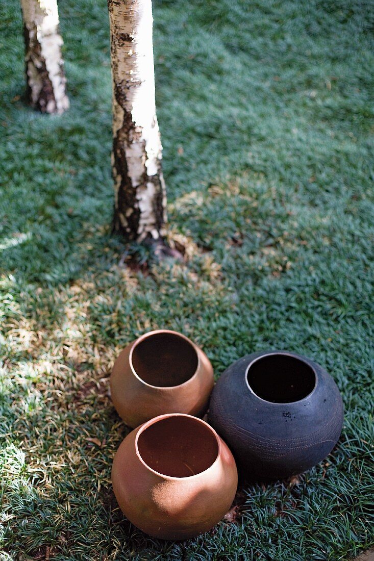 Group of clay pots of various colours on lawn