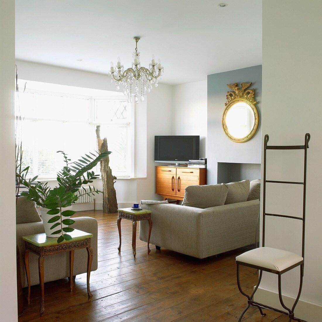 Möbelstilmix im Wohnraum mit zierlichem Eisenstuhl und Beistellstischen im Rokokostil neben modernen Polstersofas