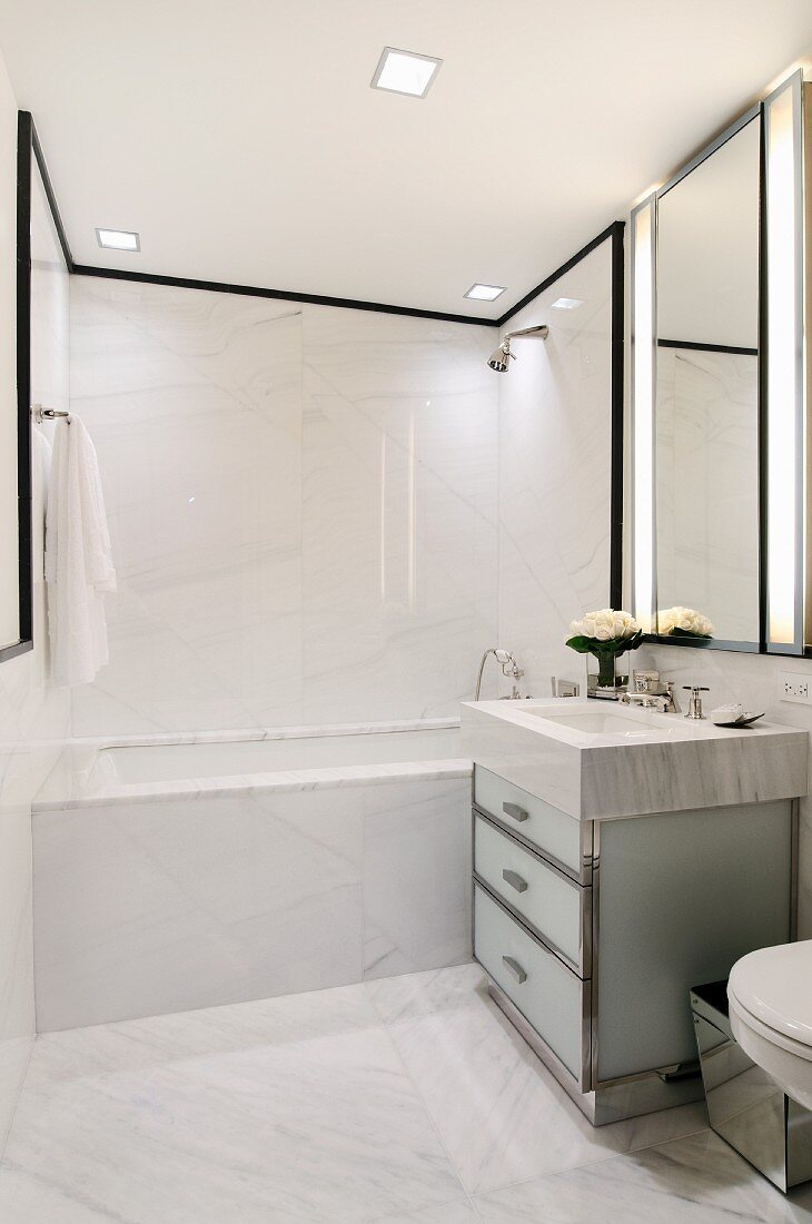 Designer marble bathroom - washstand with marble surround and glass base unit next to bathtub