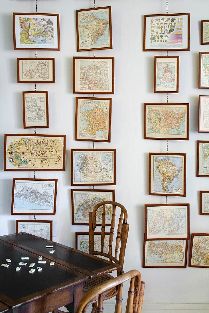 Bilder übereinander am Drahtseil vor Wand aufgehängt und traditioneller Holztisch mit Stühlen aus dunklem Holz