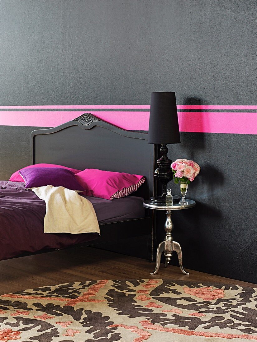 Farbkontrast schwarz mit Pinkstreifen in Schlafzimmer mit gestrichenem Antikbett und postmodernem Silbertisch