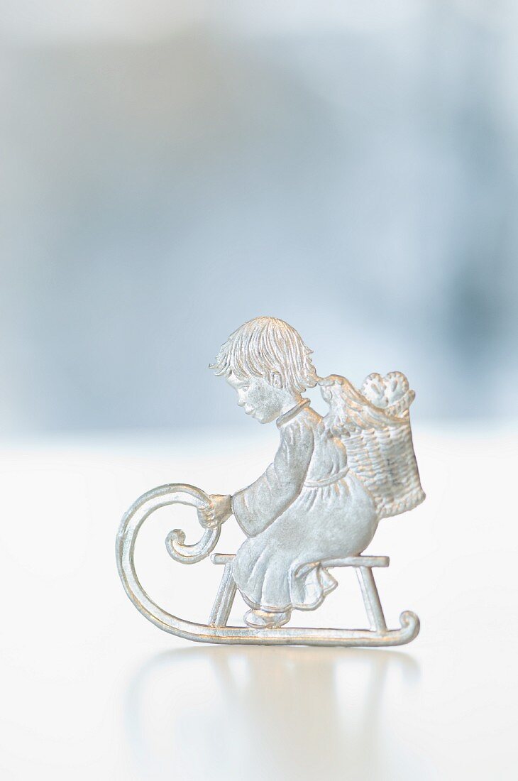 A tin Christmas figurine: a boy on a sleigh