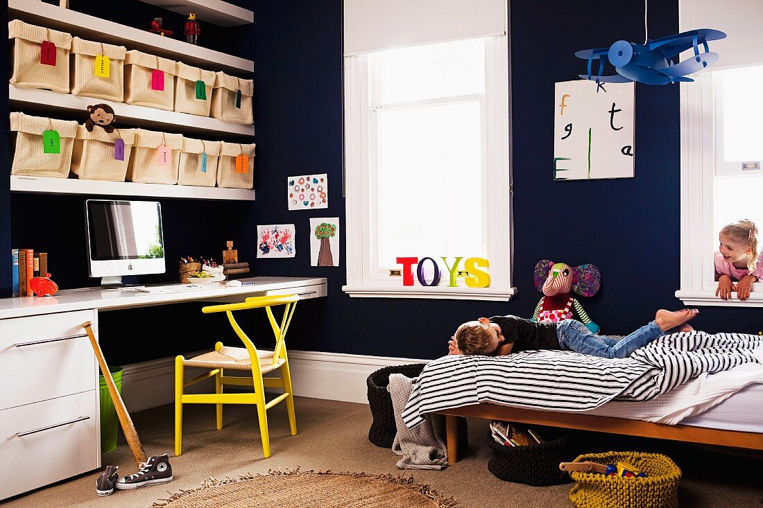 Children's room with storage system - fabric storage bins in shelves above the desk