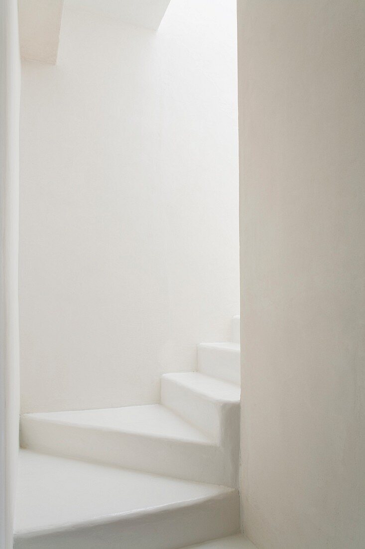 Gewendelter Treppenaufgang als puristische, weiße Raumskulptur