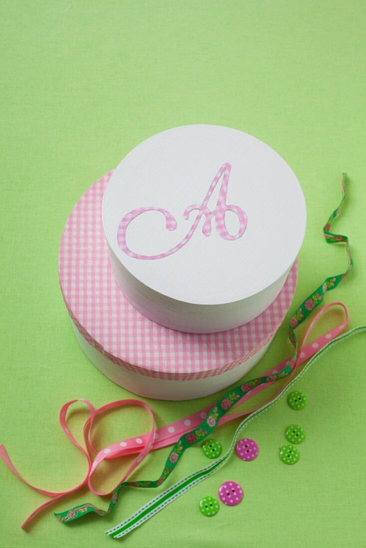 Ribbons, buttons and two decorative pink boxes, one decorated with the letter A