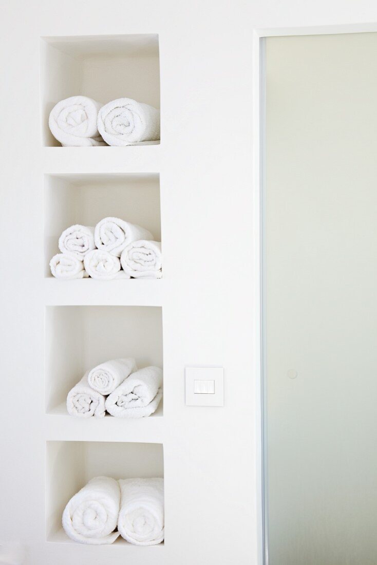 weiße Handttuchrollen in weißen quadratischen Wandnischen