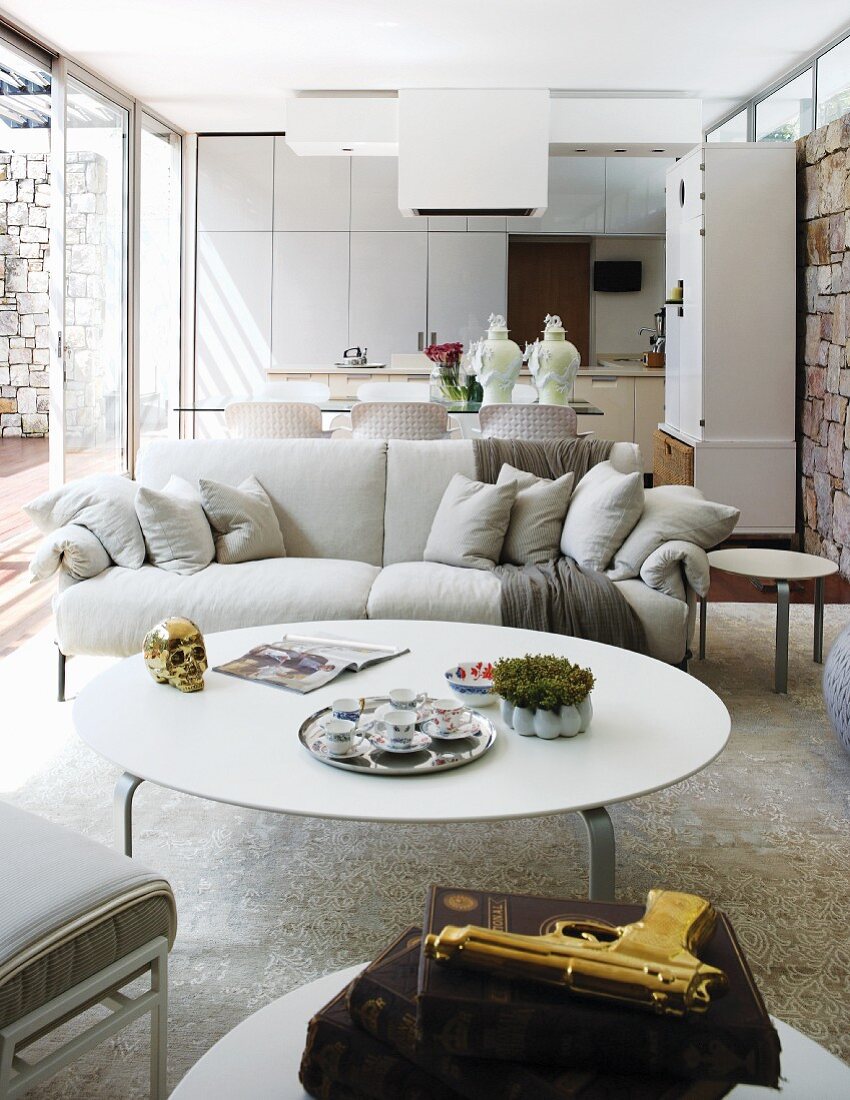 Im italienischen Designerstil eingerichteter, offener Wohnraum mit Natursteinwänden und Glasschiebetüren zur Terrasse