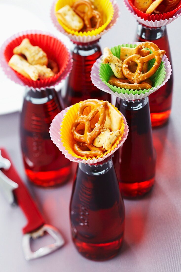 Kleine Tapas-Bar: Knabberzeug in Muffinförmchen auf Getränkeflaschen