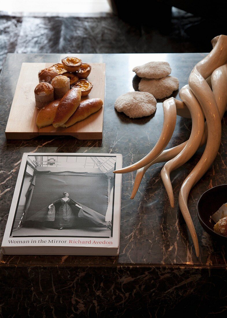 Still-life arrangement of book, pastries and hunting trophies on marble table