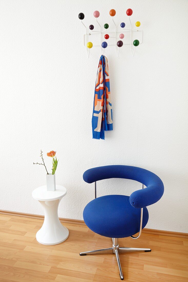 Bauhaus Drehstuhl mit blauem Bezug und Beistelltisch vor Wand mit gehängter Klassiker Garderobe