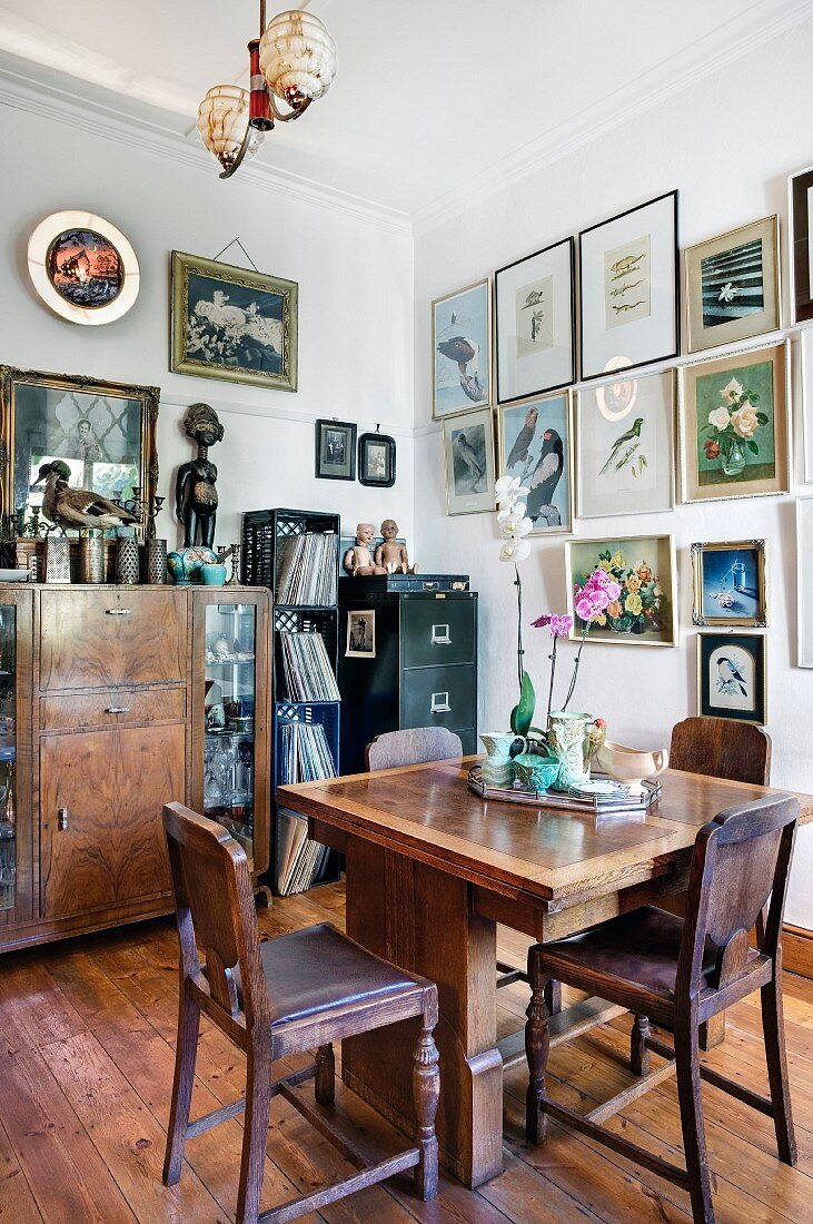 Esszimmer mit edlen Vintagemöbeln, einer Bildersammlung an der Wand und verschiedenen Kunstgegenständen