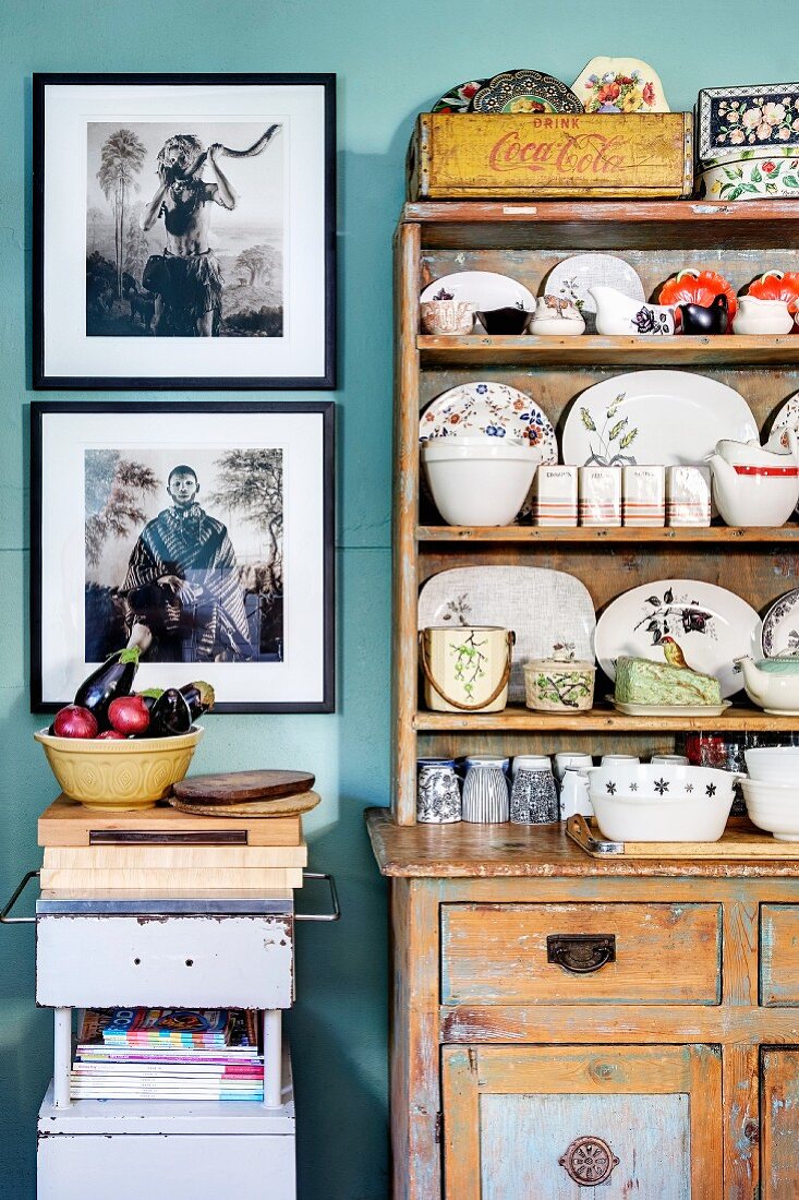 Küchenbuffet im Shabby Stil mit gesammeltem Porzellangeschirr und gerahmter Fotokunst an der Wand