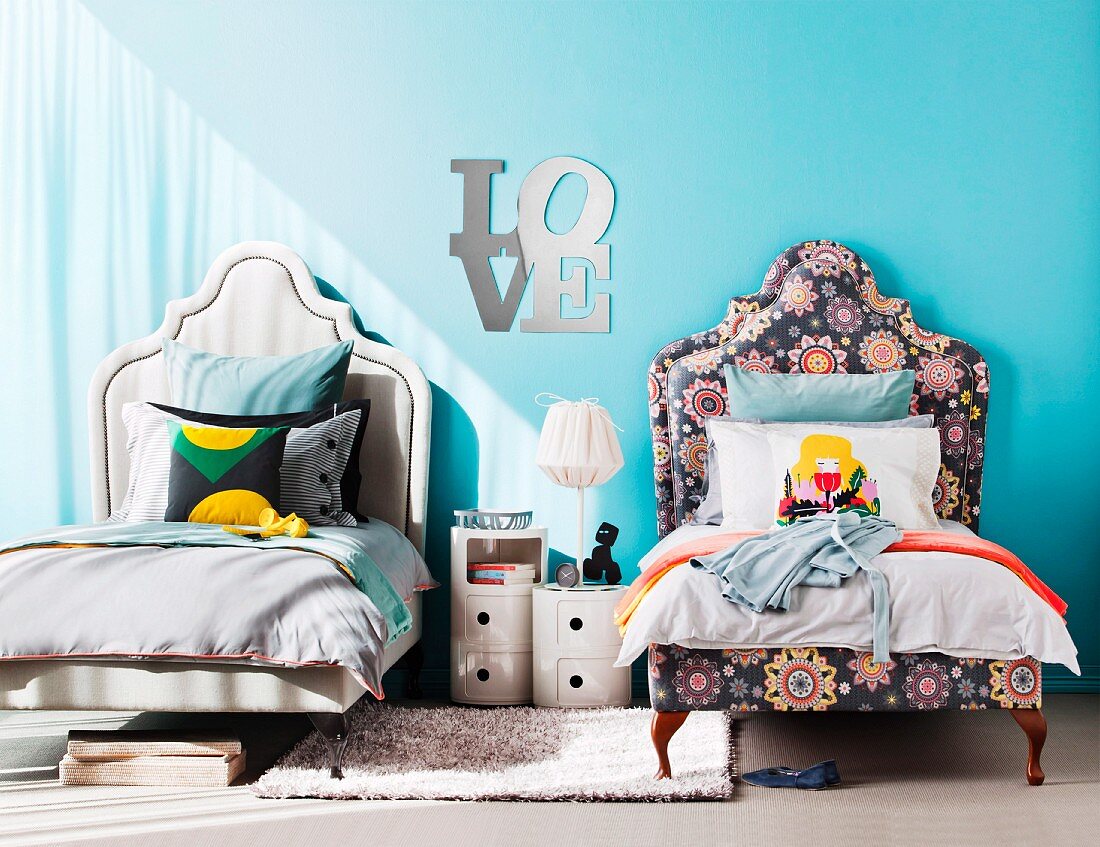 Verschieden gestaltete Geschwister-Betten mit geschwungenem Kopfteil; Buchstabenspiegel LOVE und ein neutraler Teppich als Verbindungselemente