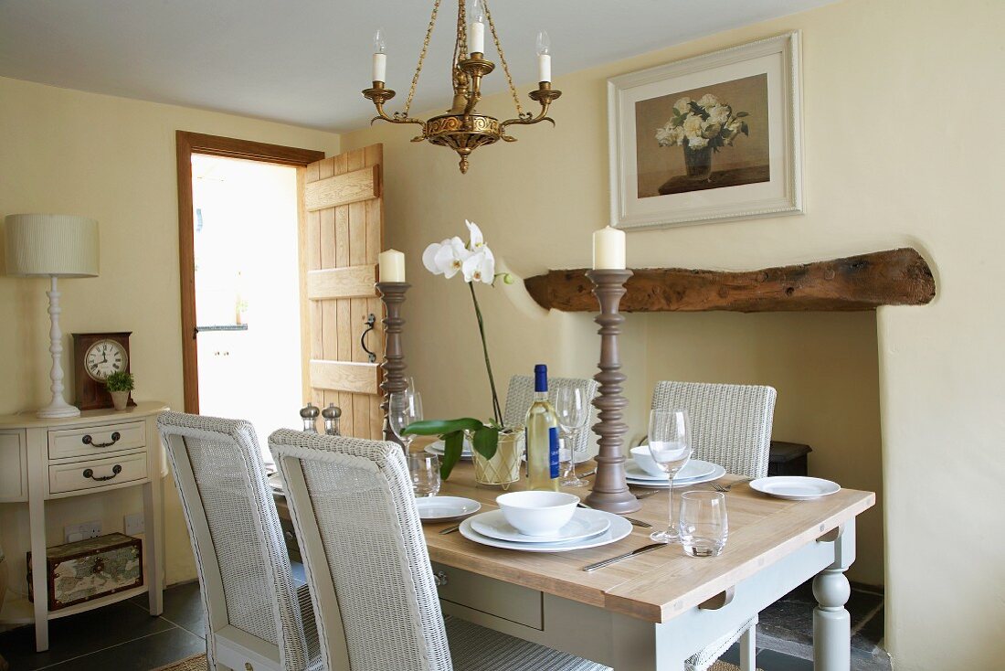 Esszimmer mit weissen Korbstühlen an gedecktem Landhaustisch in elegantem Ambiente