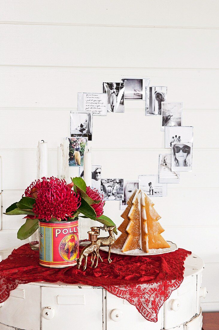 Lebkuchenbaum, Rehfiguren als Kerzenhalter und Nadelkissen-Protea in Konservendose als australische Adventsdeko vor schwarzweissen Familienbildern