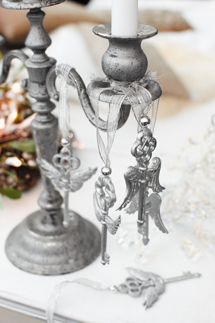 Key-shaped ornaments hanging from metal candlestick on table