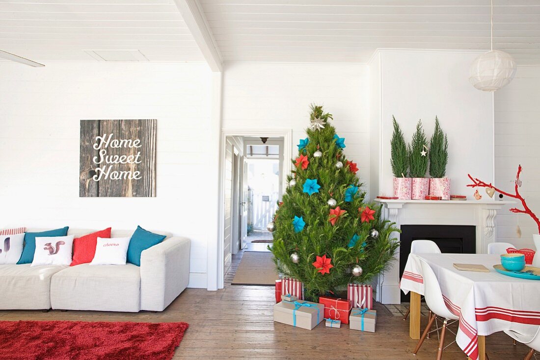 Weihnachtsbaum und Geschenke neben dem Kamin in einem Wohnraum