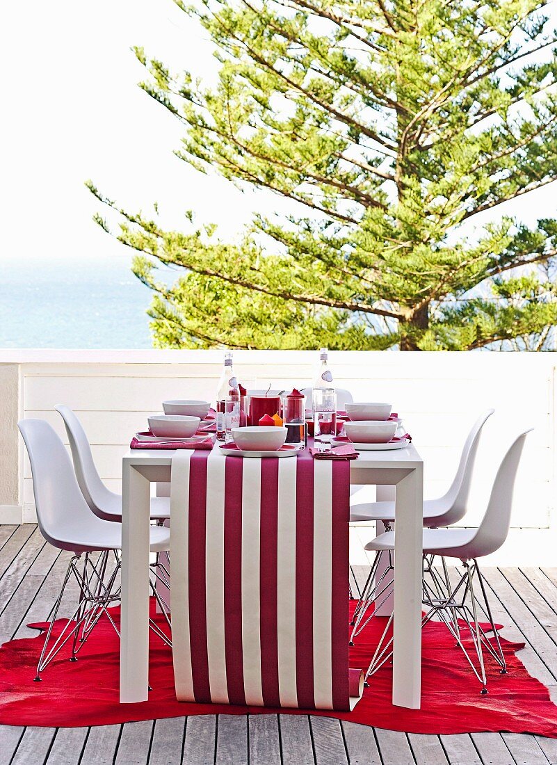 Set table on balcony with red and white striped wallpaper as table runner