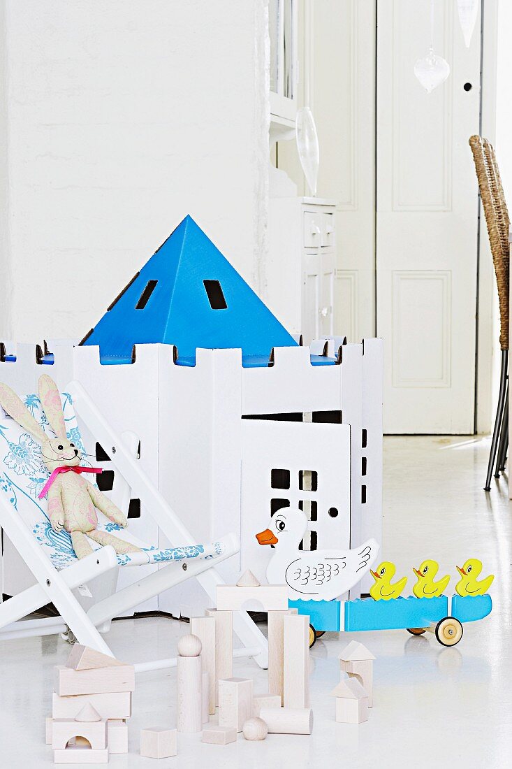 Spielzeugburg aus Karton, Bauklötze und Kinderstuhl mit Stofftier
