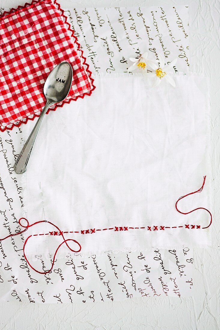 Weisses Deckchen mit roter Stickerei und Marmeladenlöffel