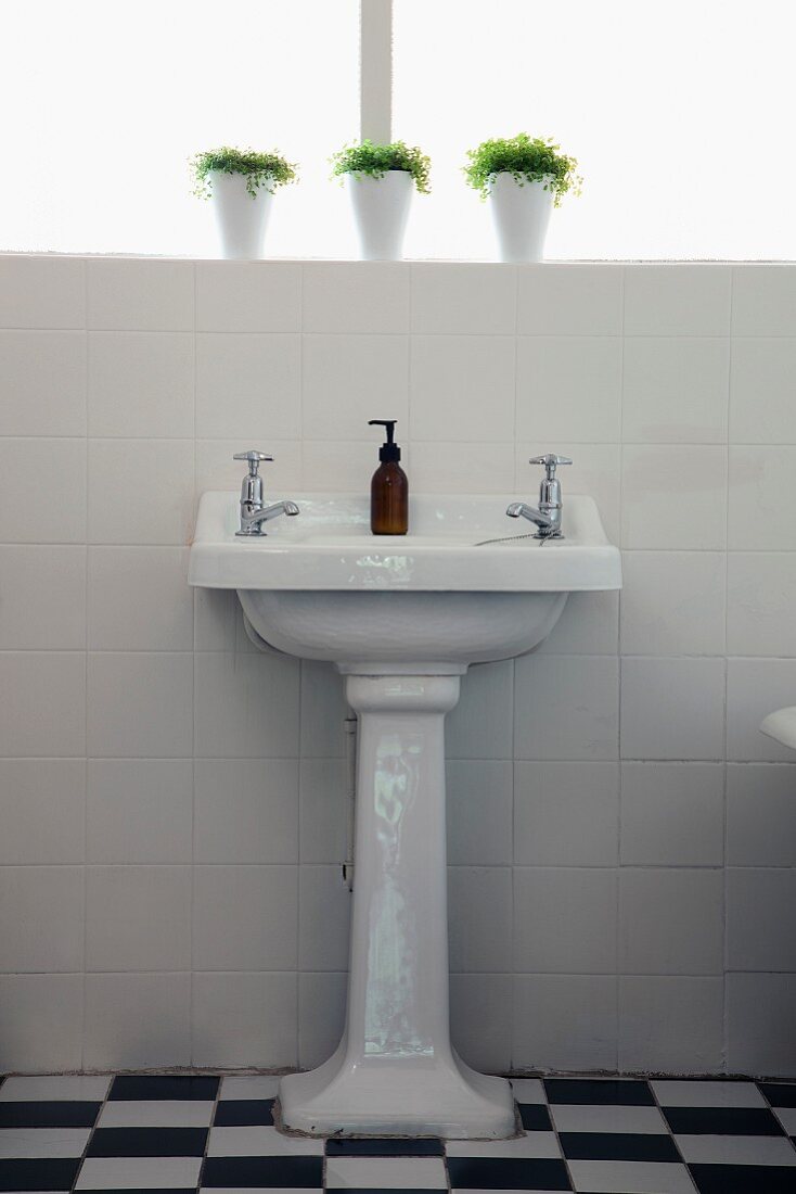 Pedestal wash basin against white-tiled wall