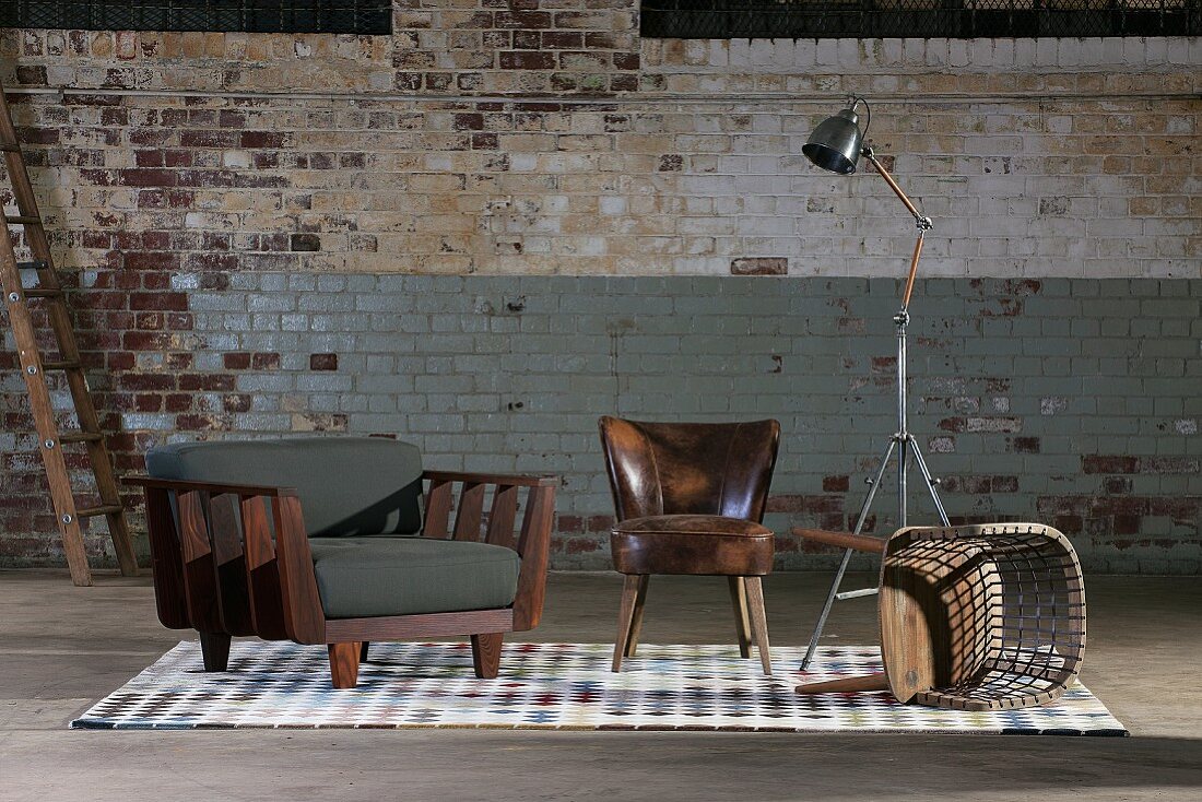 Armchairs, tipped over wooden chair and retro standard lamp against old brick wall