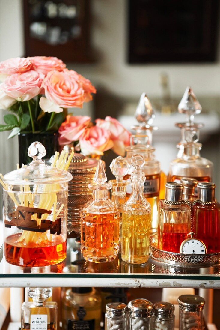 Parfumflakons und Raumduftspender mit Rosensträussen auf der Glasplatte