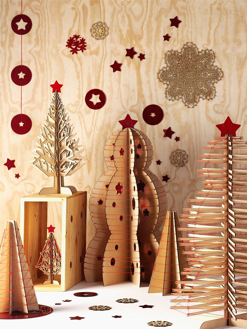 Kunstvolle Weihnachtsbaum-Objekte aus Sperrholz mit roten Stabilisierungs-Fäden und Sternendeko