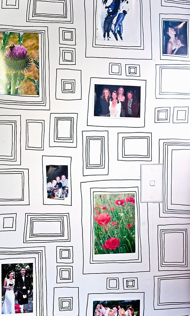 Auf Zimmerwand aufgemalte Rahmen in unterschiedlichen Größen mit drapierten Erinnerungsfotos
