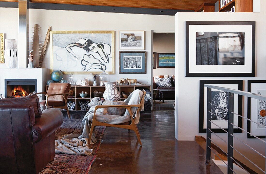 Verschiedene Sesseln in Loungebereich und moderne Bildersammlung an Wänden in offenem Wohnraum