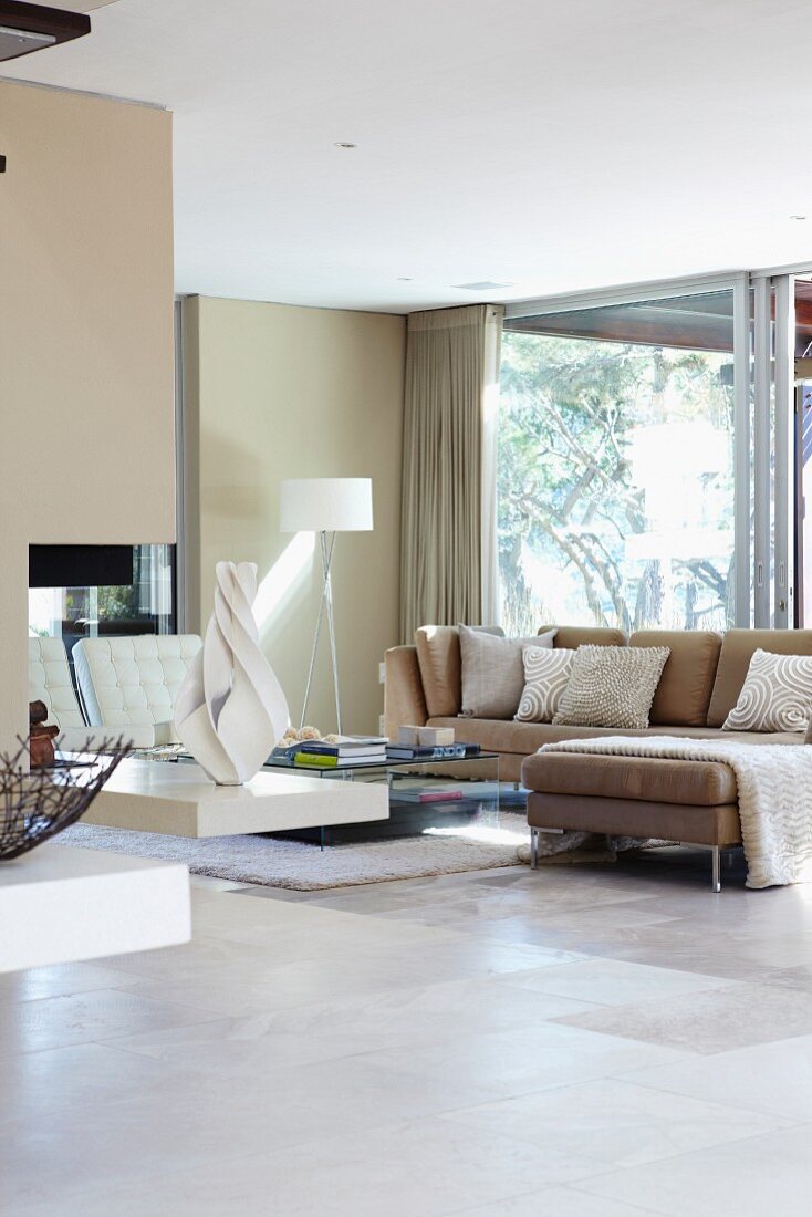 Bright interior in natural shades with sofa combination next to glass wall