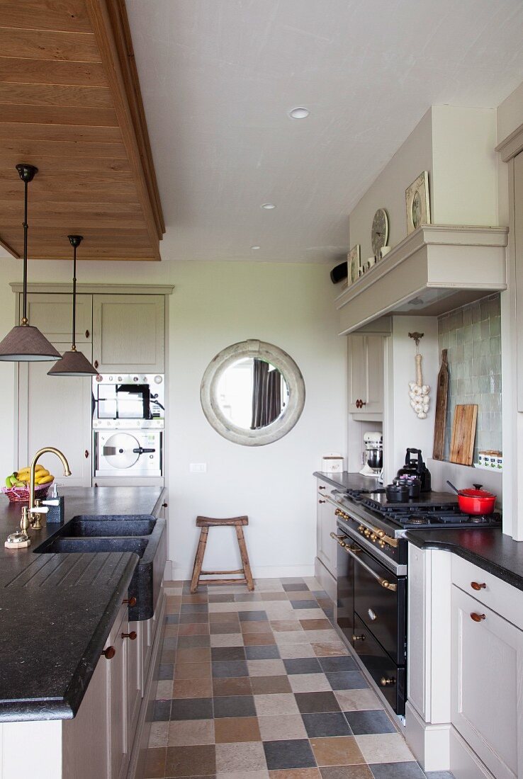 Retro-style, combination gas-electric cooker and sink unit with charcoal stone counter in county-house kitchen with marble floor tiles in natural colours